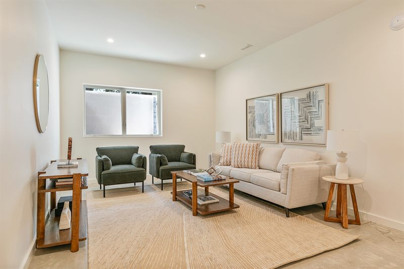 Living room with a cream sofa, two olive green armchairs and a jute rug under a pair of framed prints