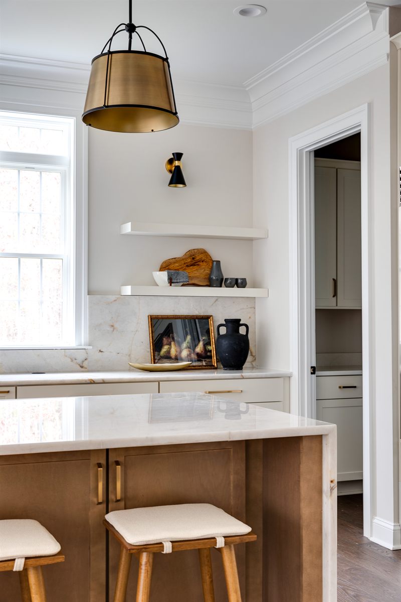 Kitchen with a brass pendant, floating shelves over a marble backsplash and a wood island with stools