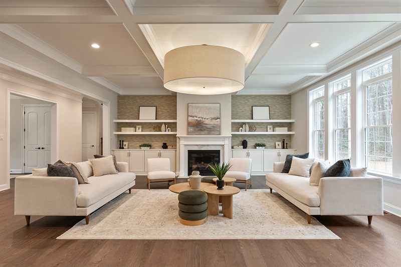 Living room with a coffered ceiling, two facing cream sofas and built-in shelves either side of the fireplace