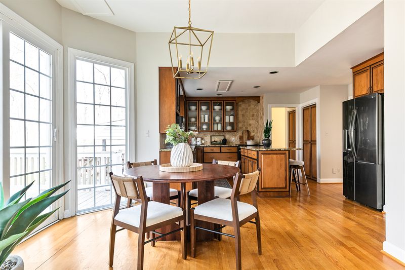 Breakfast nook with a round wood table under a brass lantern, beside doors onto the deck