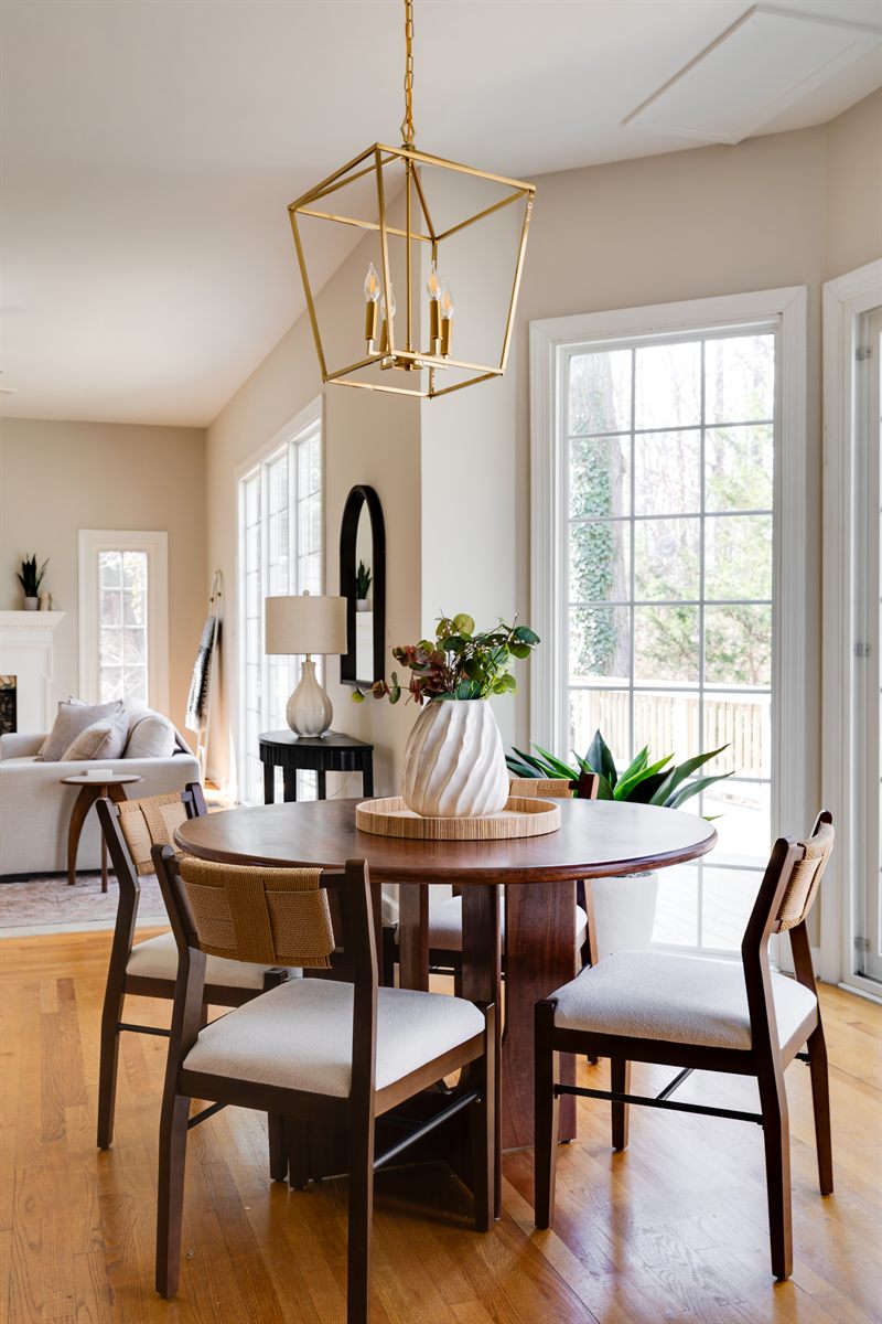 Round breakfast table with woven-back chairs under a brass lantern pendant