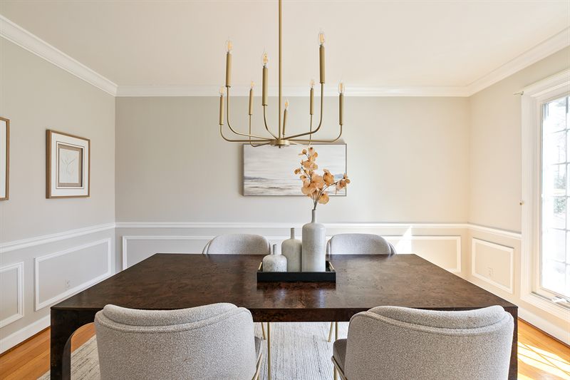 Dining room with a brass candle chandelier, wainscoting and a dark wood table
