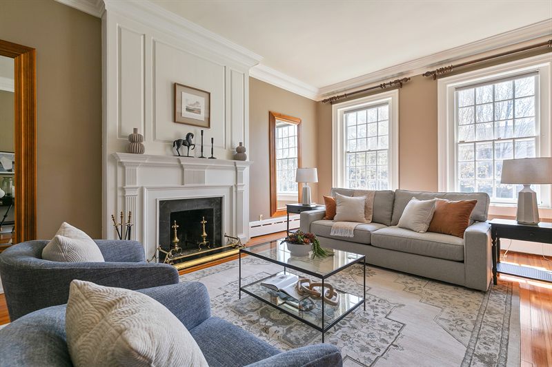 Living room with a fireplace, grey sofa, two blue armchairs and a glass coffee table