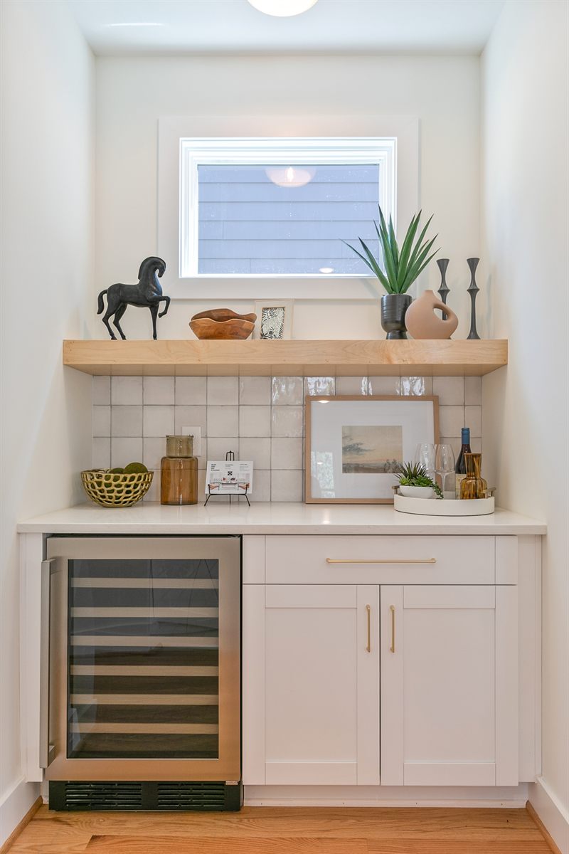 Beverage bar with a wine fridge, maple floating shelf and a bronze horse sculpture