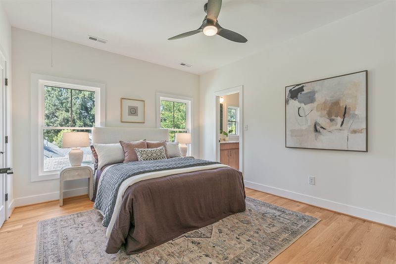 Bedroom with an upholstered headboard, brown coverlet and abstract art beside the ensuite door