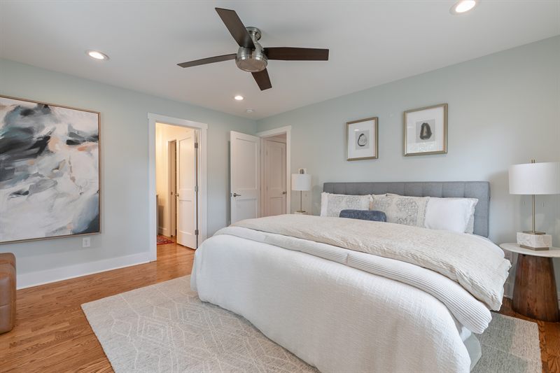 Bedroom with pale green walls, a grey upholstered bed and a large abstract canvas