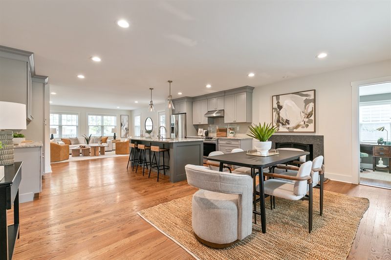 Open-plan grey kitchen with an island and stools, seen past a dining table on a jute rug